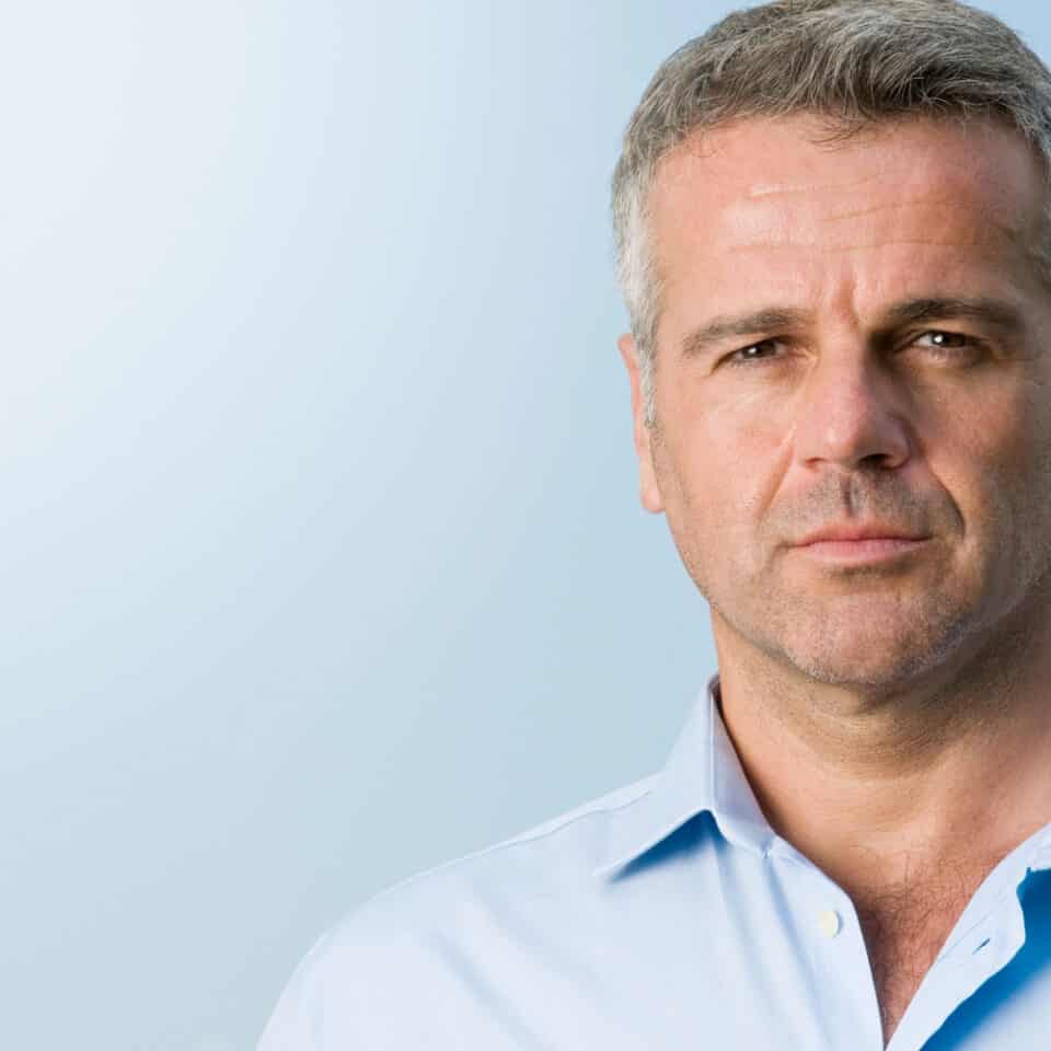 man in blue shirt looking at camera with serious expression
