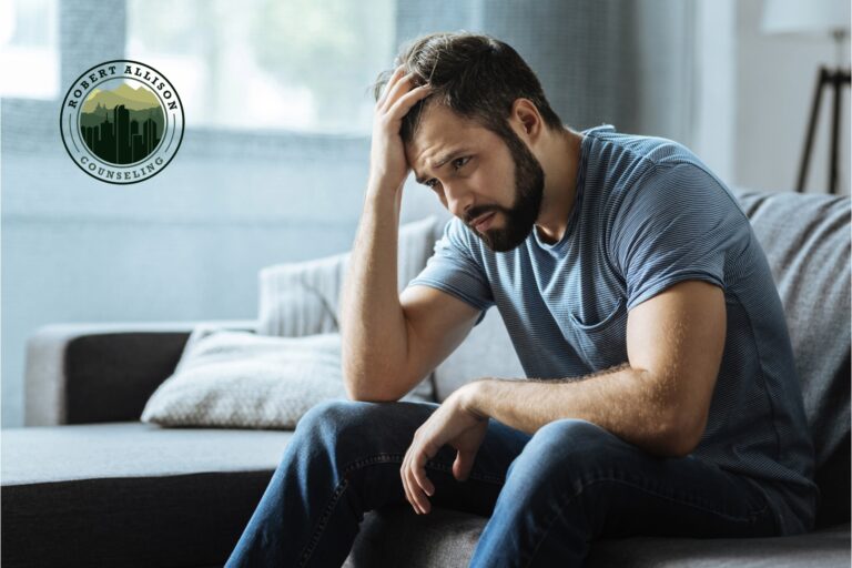 Anxious man on couch with head in hands.