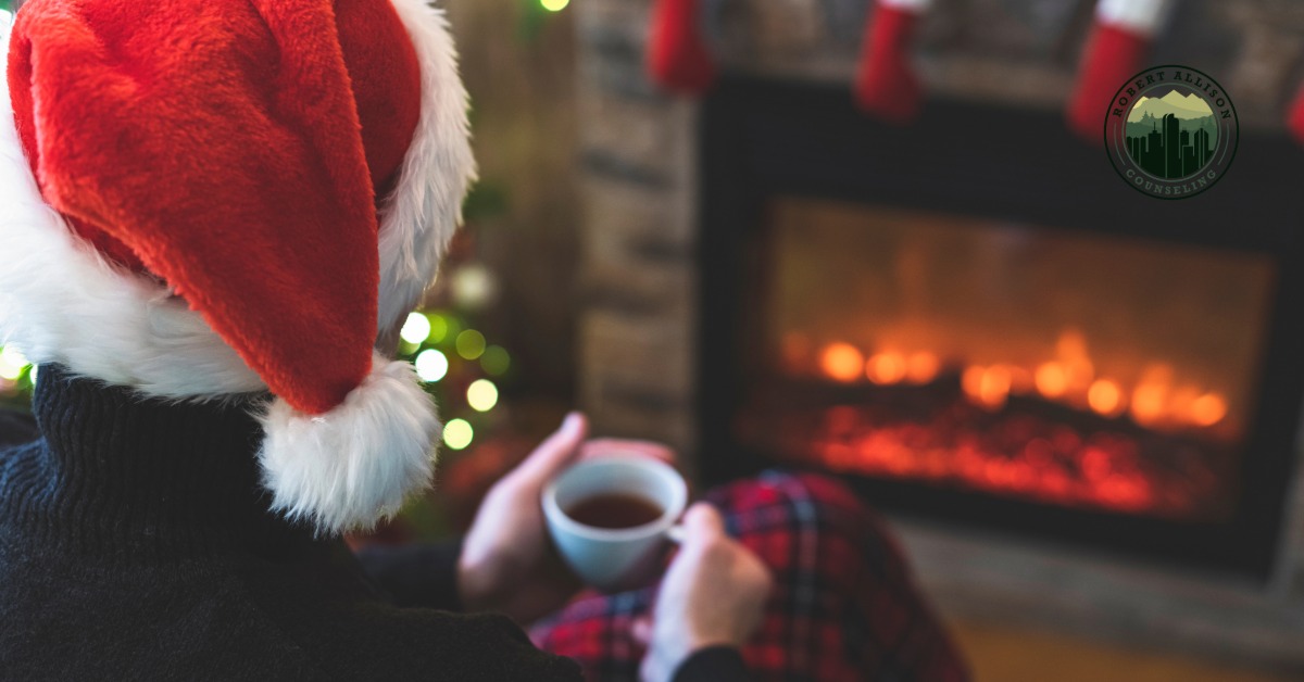 Sad man in santa hat drinking coffee and staring at fireplace