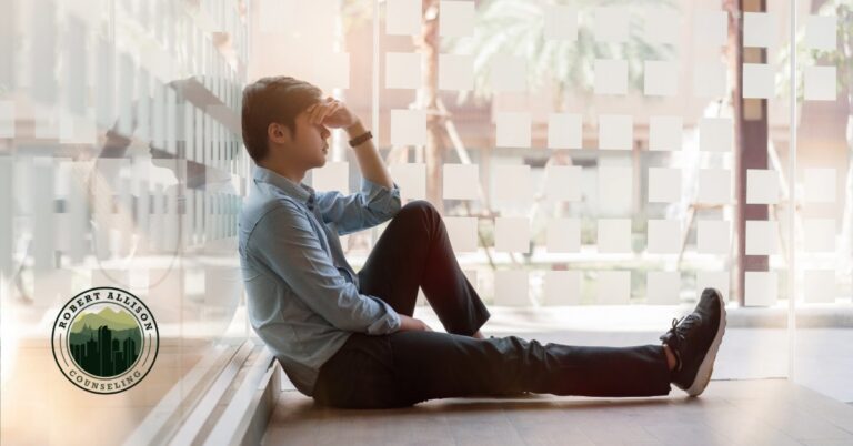 Exhausted man with head in hand on floor of office